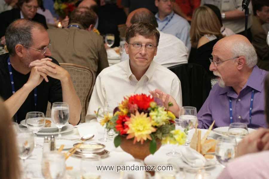 عکس بیل گیتس و استیو جابز در رستوران. در تصویر آنها سه نفر هستند و مرد سوم در حال صحبت کردن پشت میز غذاخوری و پشت سر آنها مردم و مشتریان رستوران نشسته اند. روی میز غذاخوری چند شاخه گل نیز است