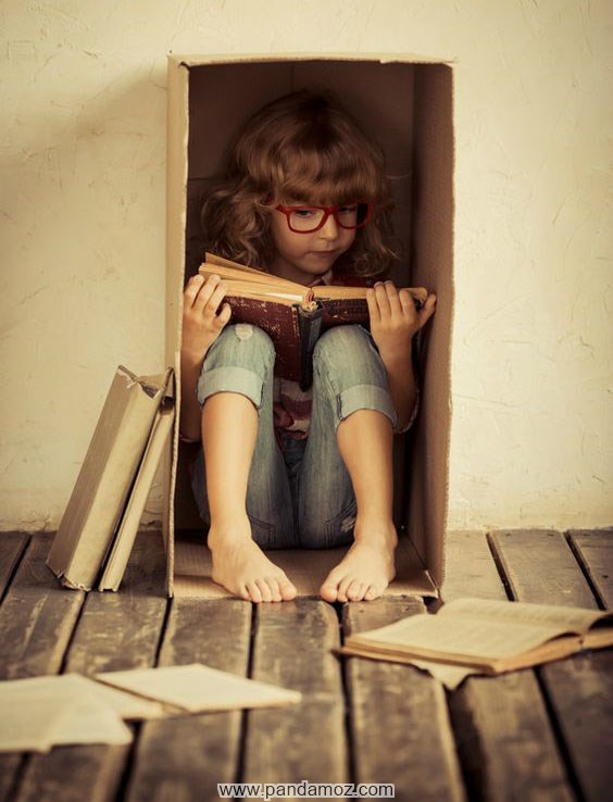 عکس کتاب خواندن دختر بچه در داخل جعبه کارتن مقوایی