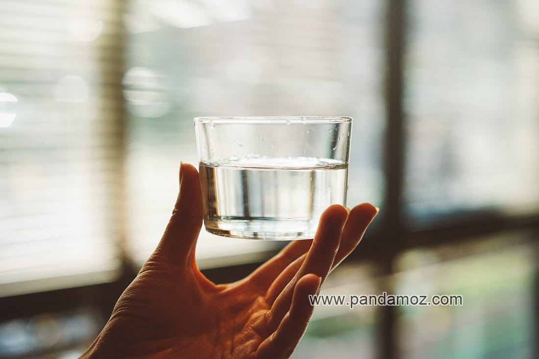 عکس لیوان کوچک آب که در دست گرفته شده و در طولانی مدت خسته کننده است