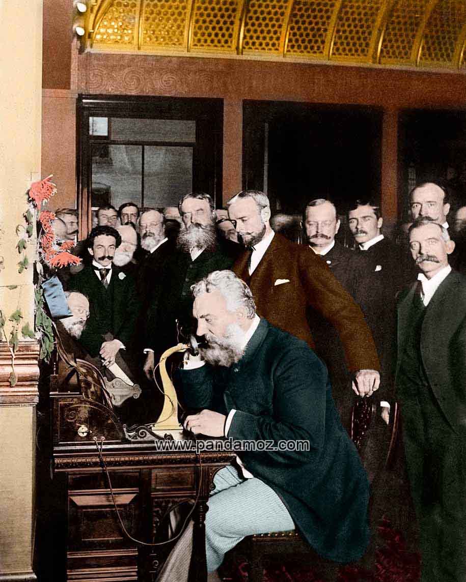 عکس رنگی شده از لحظه آزمایش تلفن به وسیله الکساندر گراهام بل مخترع تلفن در سال 1876، در تصویر جمعت زیادی سرپا ایستاده و گراهام بل در حال نشسته و مکالمه تلفن است