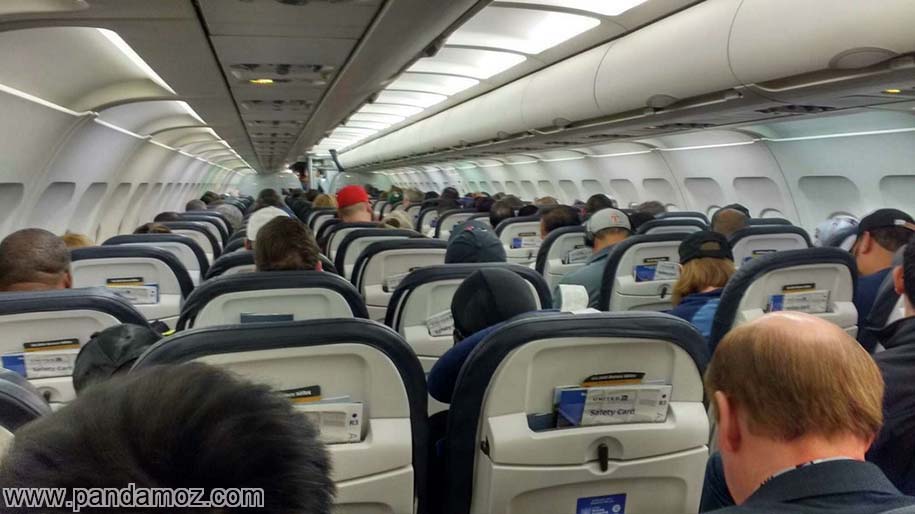 عکس مسافران نشسته در هواپیما که از پشت گرفته شده و داخل هواپیما به صورت کامل دیده می شود
