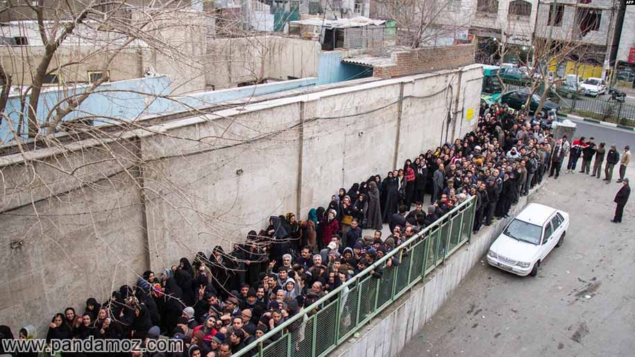 عکس مردم که برای گرفتن غذای نذری در صف طولانی ایستاده اند، صف زنها و مردها جداگانه است