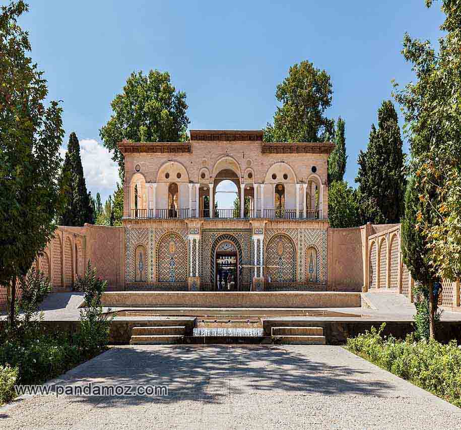 عکس نمای بیرونی از عمارت و کاخ باغ شازده یا شاهزاده در ماهان کرمان که در زمان عبدالحمید میرزا ناصرالدوله فرمانفرمایان، نوه دختری ناصرالدین شاه و حاکم کرمان ساخته شده است. در تصویر نمای ورودی و حوض آب آبنما و طاق ها اطراف و درختان دیده می شوند