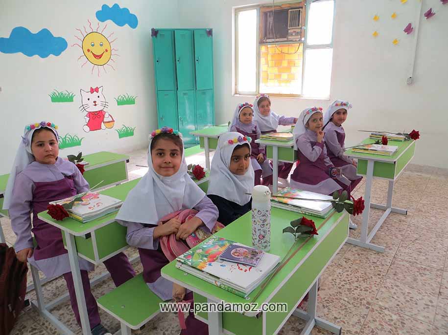 عکس کلاس درس مدرسه ابتدایی دخترانه و دخترهایی که با روپوش ها و لباس های فرم یکسان و رنگی پشت نیکمت ها نشسته اند