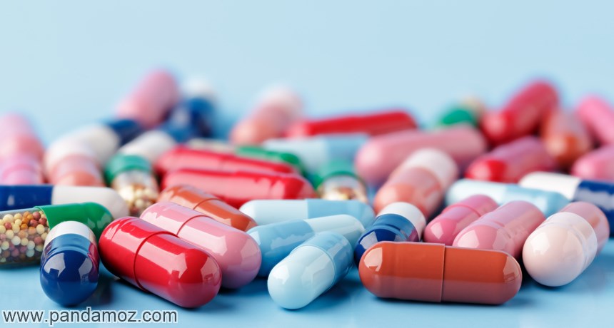 عکس قرص ها و داروهای کپسولی شکل رنگارنگ روی میز. در تصویر چند کپسول که در داخل آنها دانه های ریز دوا دیده می شوند