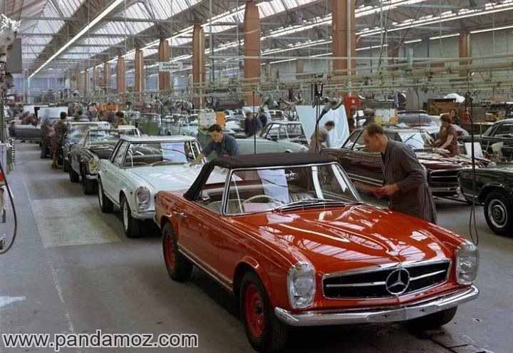 عکس سالن مونتاژ اتومبیل سواری کارخانه بنز آلمان در زمان قدیم. در مقابل تصویر یک ماشین بنز مدل قدیمی قرمز رنگ دیده می شود و در پشت آن دهها ماشین سواری بنز و کارگزارن مونتاژکار دیده می شوند