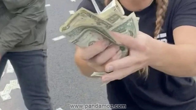 عکس دلارهای ریخته شده در خیابان و مردمی که در حال جمع کردن و برداشتن دلارها هستند. در تصویر یک زن تعداد زیادی اسکناس دلار در دستش گرفته و مجاله کرده و نشان می دهد