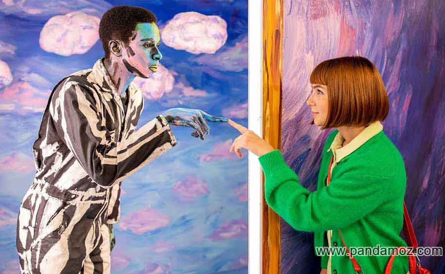 نقاشی عکس زن و مرد در آینه. زنی که لباس سبز رنگ پوشیده با انگشت به آینه زده و مرد داخل آینه همان حرکت را متقابل انجام می دهد
