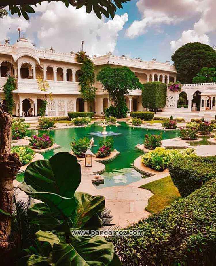 عکس تابلو نقاشی از باغی زیبا با عمارت و کاخی بی نظیر در داخل آن و تصویری از حوض وسیع و بزرگ پر از آب و گیاهان و گلها و درختان سرسبز و آسمان آبی و ابرهای باران زا