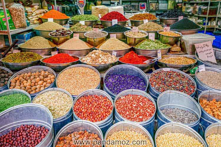 عکس مغازه عطاری و ادویه فروشی در تبریز. در تصویر ادویه ها و داروهای گیاهی متنوع و در ظروف بزرگ فلزی و سایر خوردنیها و چاشنی ها با رنگهای گوناگون و شاد دیده می شوند