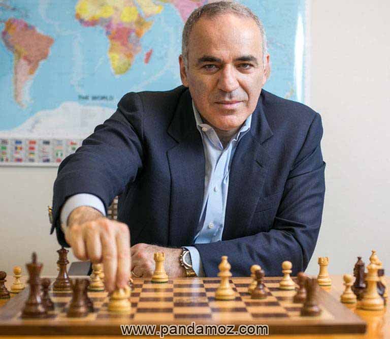 عکس کاسپارف شطرنج باز معروف روسیه. در تصویر در حالی که او در حالت نشسته و به دوربین نگاه می کند در حال حرکت داده مهره شطرنج روی میز است