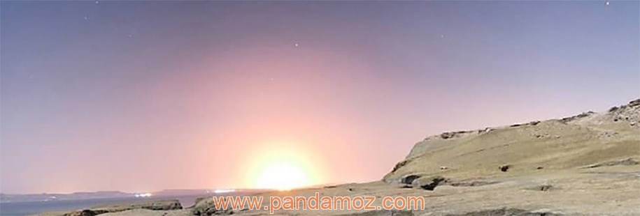 عکس دریا و جزیره زیبا. در تصویر آفتاب در حال طلوع یا غروب خورشید به همراه موج های دریا و ساحل صخره ایی و سنگی دیده می شود